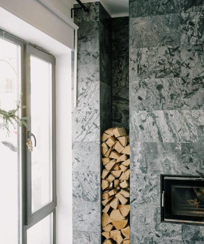 Cozy modern living room featuring a sleek fireplace and a neatly stacked woodpile.